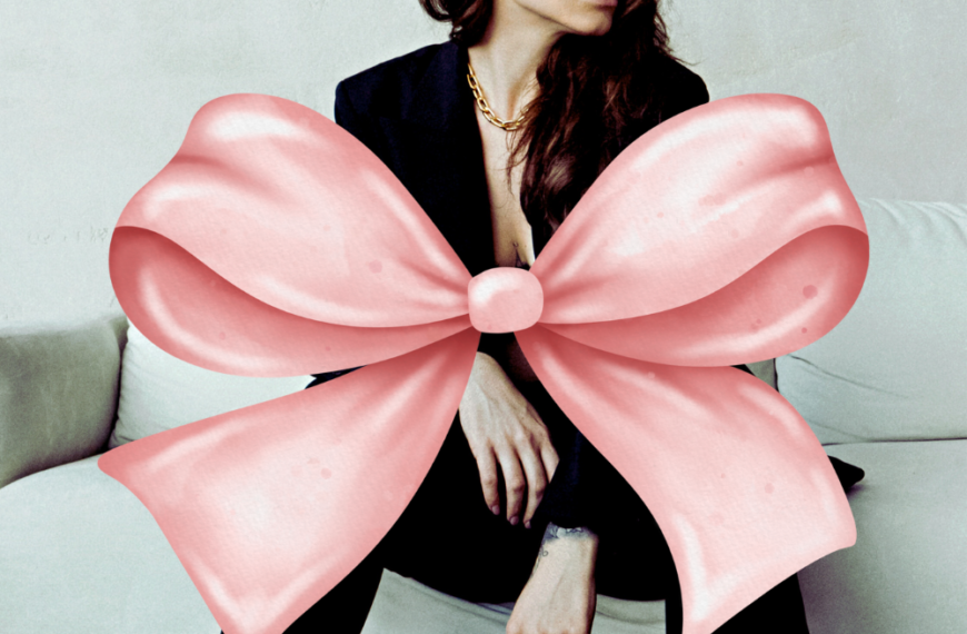 Woman with a massive pink bow in a black suit.